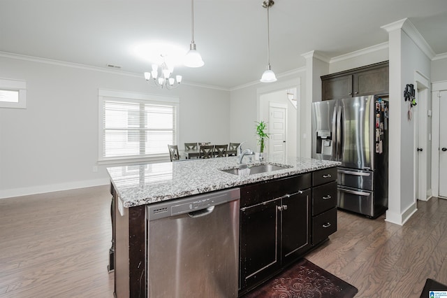 kitchen featuring appliances with stainless steel finishes, dark wood-type flooring, a kitchen island with sink, ornamental molding, and sink