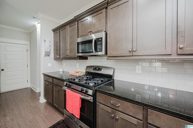 kitchen with dark hardwood / wood-style flooring, stainless steel appliances, dark brown cabinets, dark stone counters, and ornamental molding