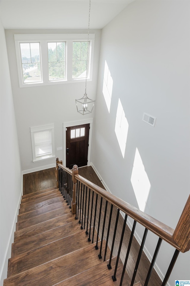 staircase featuring hardwood / wood-style flooring, a high ceiling, a chandelier, and a wealth of natural light