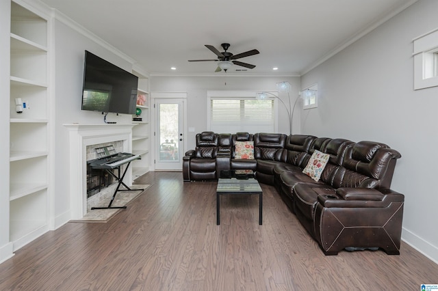 living room featuring built in features, ceiling fan, hardwood / wood-style flooring, and crown molding