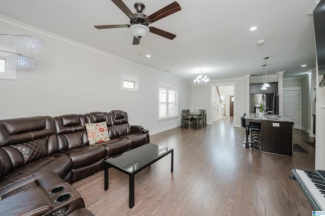 living room featuring ornamental molding, ceiling fan with notable chandelier, dark hardwood / wood-style floors, and sink