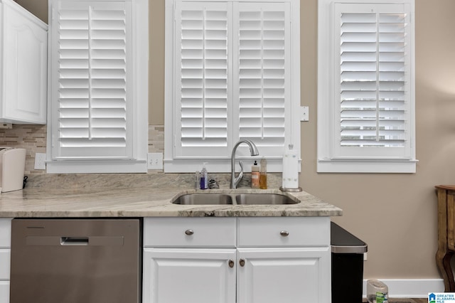 kitchen featuring white cabinetry, light stone counters, backsplash, stainless steel dishwasher, and sink