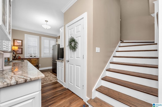 stairs featuring wood-type flooring, sink, and crown molding