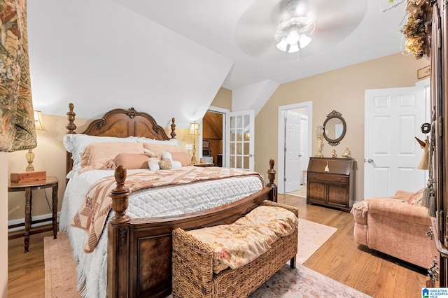 bedroom with light hardwood / wood-style flooring, vaulted ceiling, and ceiling fan