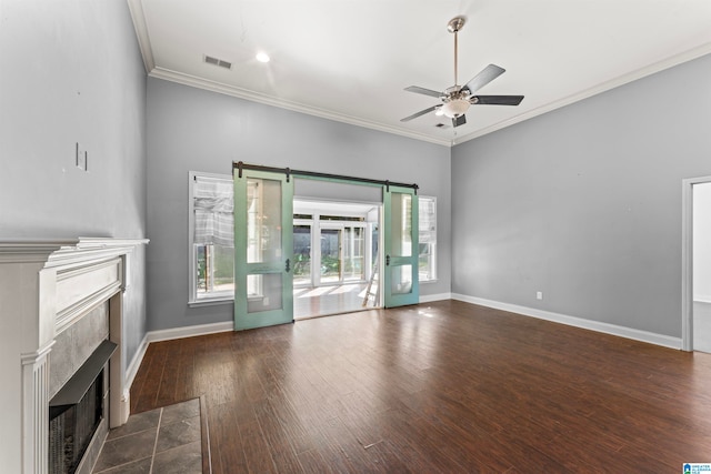 unfurnished living room with a barn door, dark hardwood / wood-style flooring, a high end fireplace, and plenty of natural light