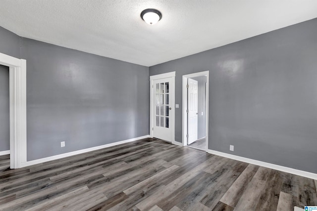 spare room with a textured ceiling and dark hardwood / wood-style flooring