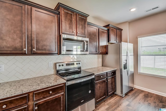 kitchen featuring dark brown cabinets, hardwood / wood-style flooring, appliances with stainless steel finishes, and backsplash