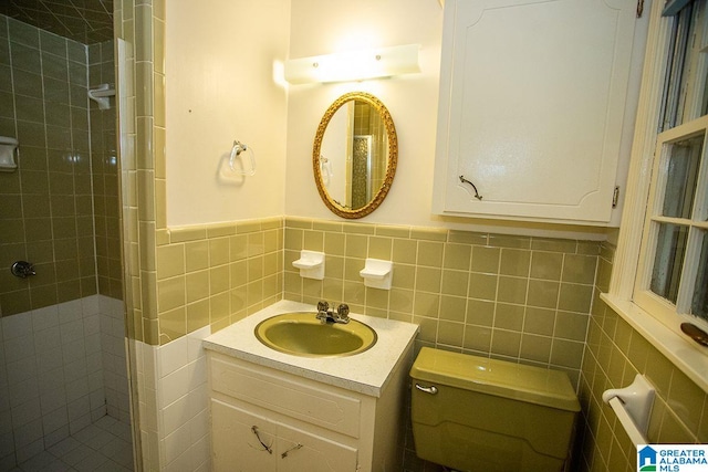 bathroom with tile walls, tiled shower, vanity, and toilet