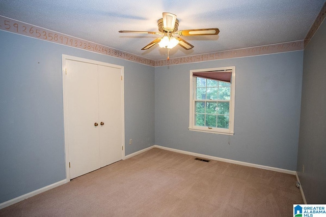 carpeted spare room featuring ceiling fan and a textured ceiling