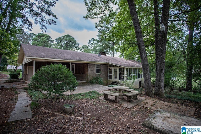 rear view of house featuring a sunroom and a patio