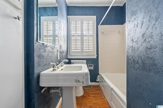 bathroom with hardwood / wood-style flooring, crown molding, toilet, and bathing tub / shower combination