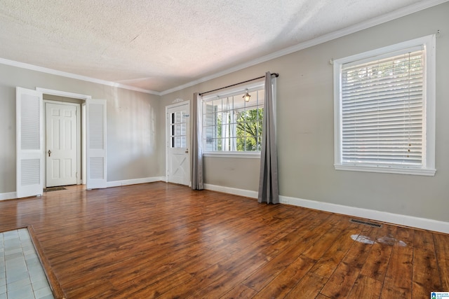 spare room featuring ornamental molding, a textured ceiling, and dark wood-type flooring