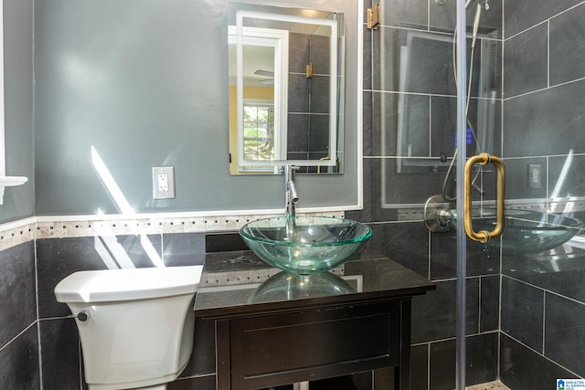 bathroom with vanity, tile walls, a shower with shower door, and toilet