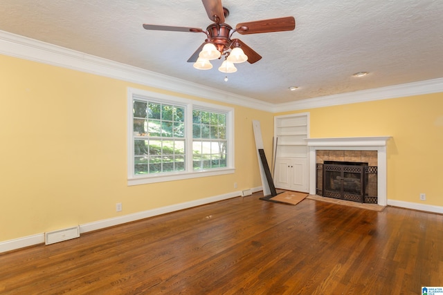 unfurnished living room featuring ceiling fan, ornamental molding, a textured ceiling, hardwood / wood-style flooring, and a fireplace