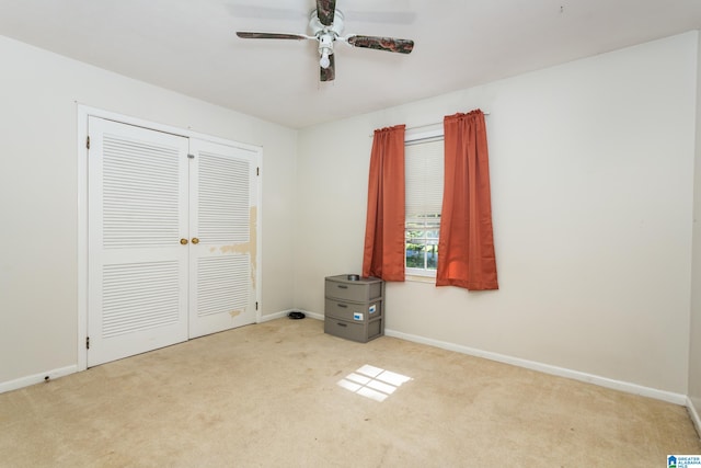 unfurnished bedroom featuring ceiling fan, light colored carpet, and a closet