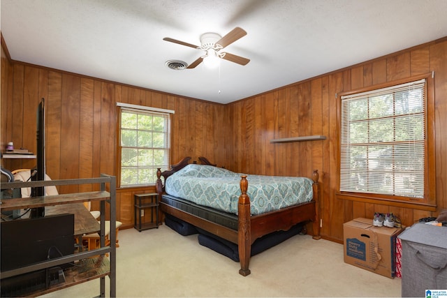 carpeted bedroom featuring ceiling fan, a textured ceiling, and wooden walls