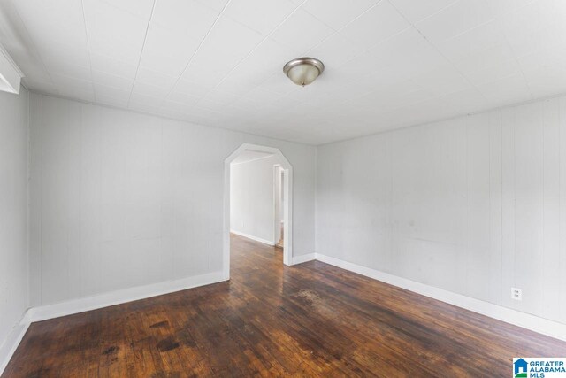 bonus room with wooden walls and dark wood-type flooring