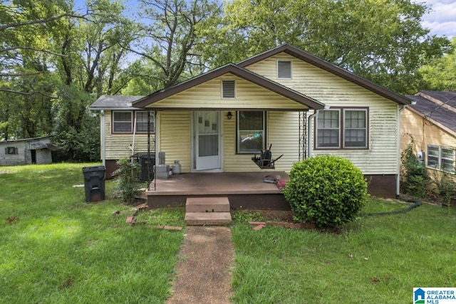 bungalow-style home featuring a storage shed, a front lawn, and a wooden deck