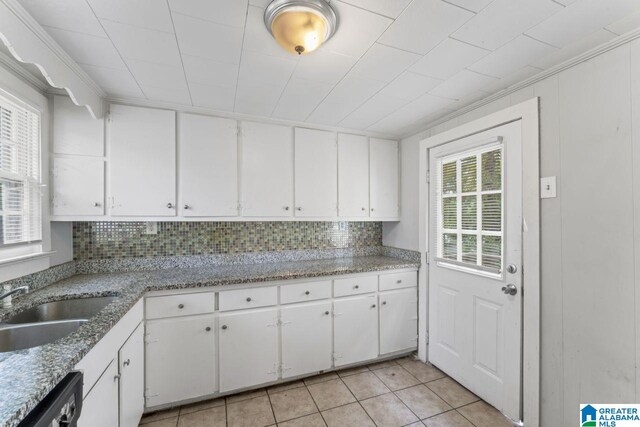 kitchen featuring sink, white cabinets, decorative backsplash, light tile patterned floors, and dishwashing machine