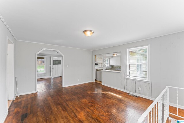 unfurnished living room with ornamental molding and dark wood-type flooring