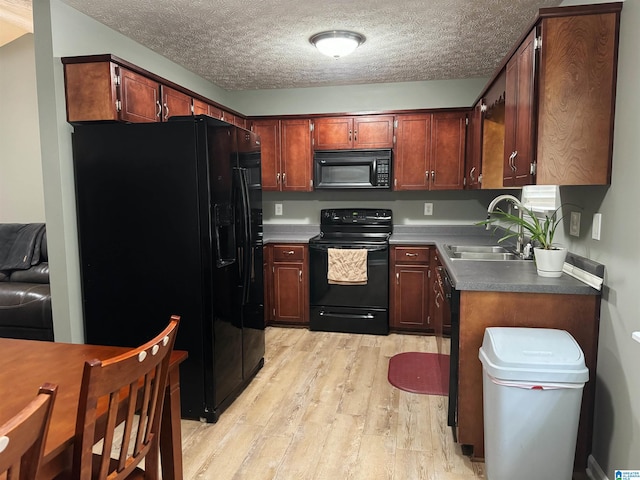 kitchen featuring sink, light hardwood / wood-style floors, a textured ceiling, and black appliances