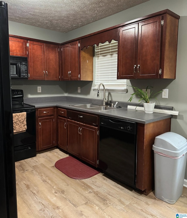 kitchen with a textured ceiling, black appliances, light hardwood / wood-style floors, and sink