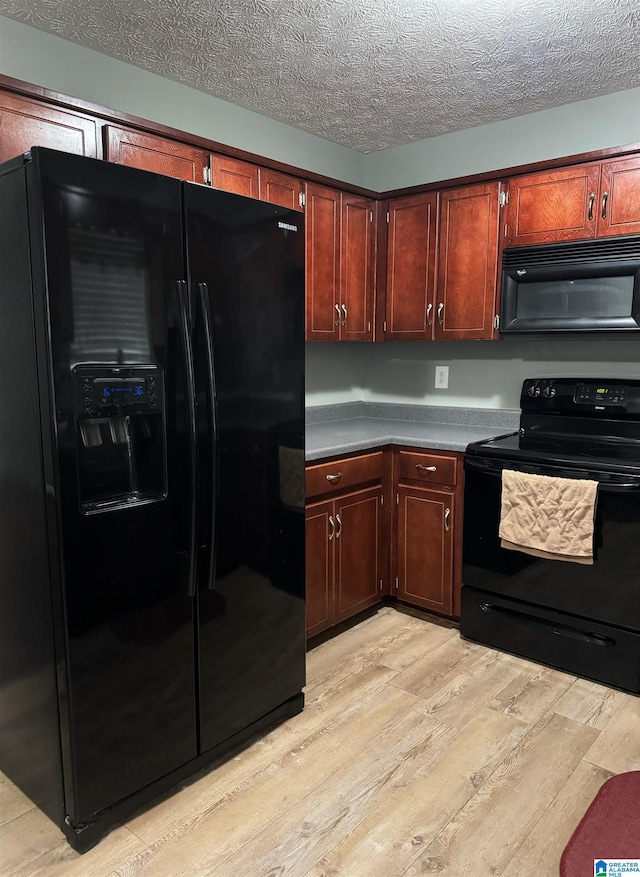 kitchen featuring a textured ceiling, light wood-type flooring, and black appliances