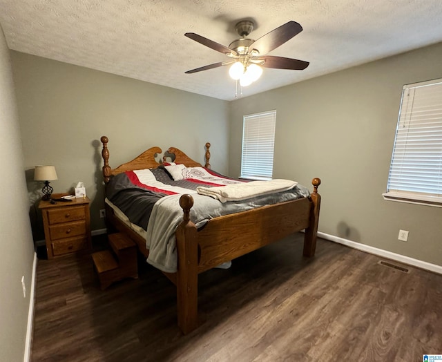 bedroom featuring ceiling fan, dark hardwood / wood-style floors, and a textured ceiling