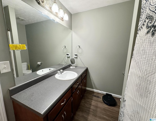 bathroom featuring hardwood / wood-style floors, a textured ceiling, vanity, and toilet