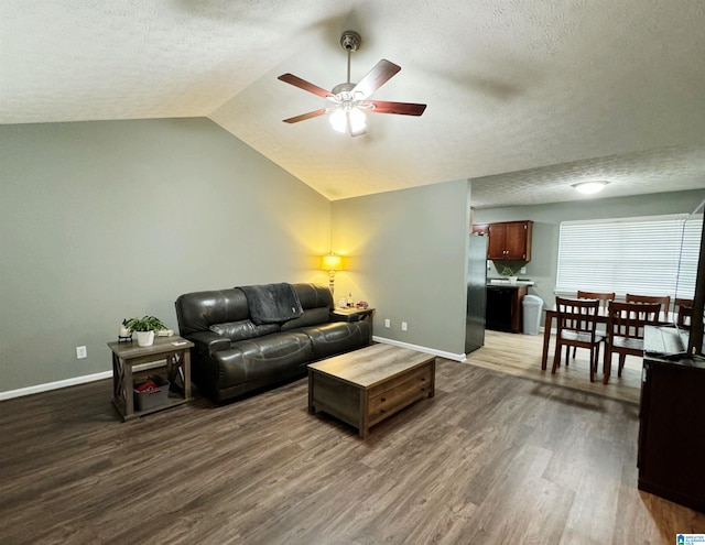 living room with wood-type flooring, a textured ceiling, vaulted ceiling, and ceiling fan