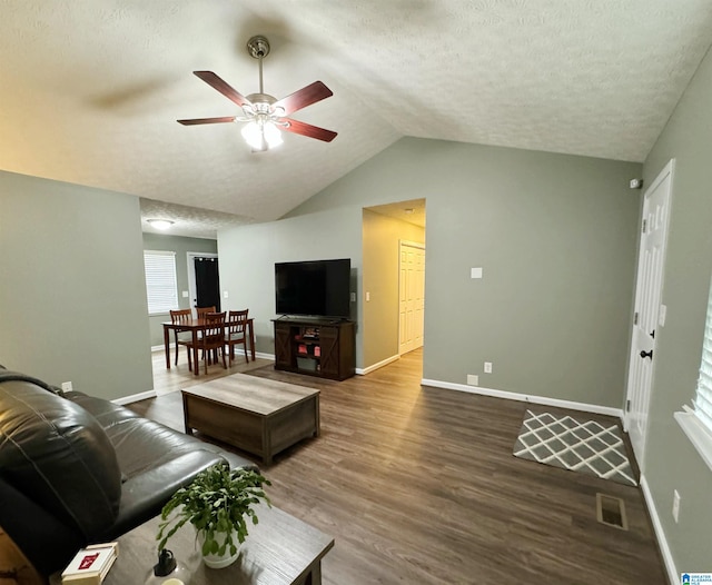 living room featuring lofted ceiling, ceiling fan, dark wood-type flooring, and a textured ceiling