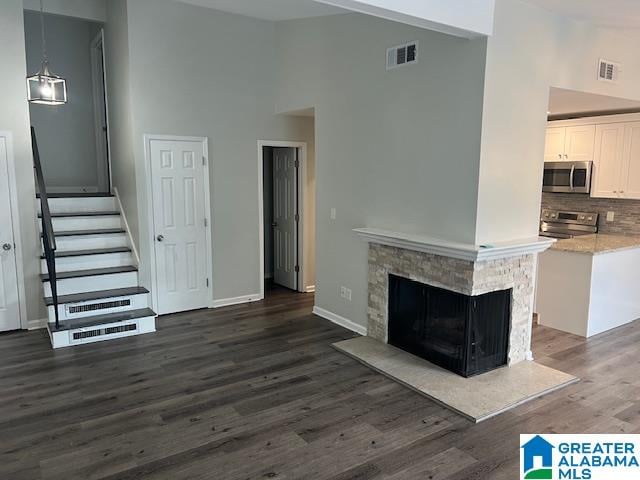 unfurnished living room with a fireplace, a high ceiling, and dark hardwood / wood-style floors