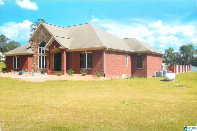 rear view of house with central AC and a yard