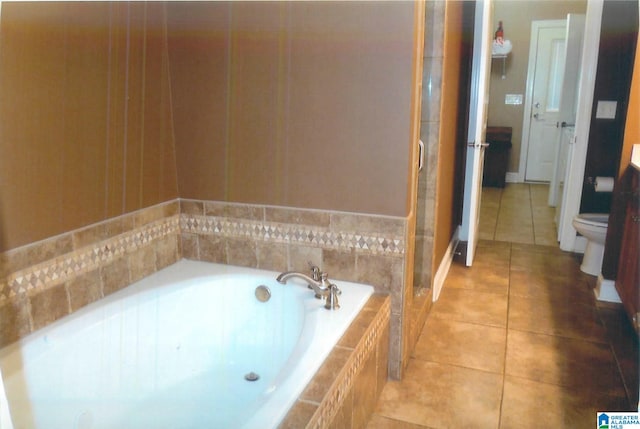 bathroom with vanity, tiled bath, tile patterned flooring, and toilet