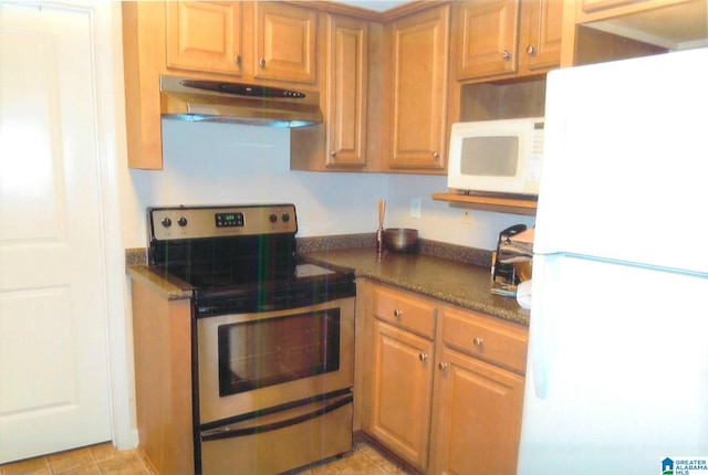 kitchen featuring light tile patterned flooring, dark stone counters, and white appliances