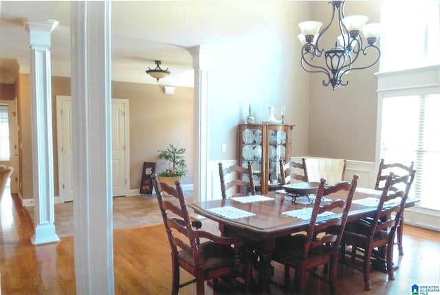 dining area with light hardwood / wood-style flooring, a chandelier, and decorative columns