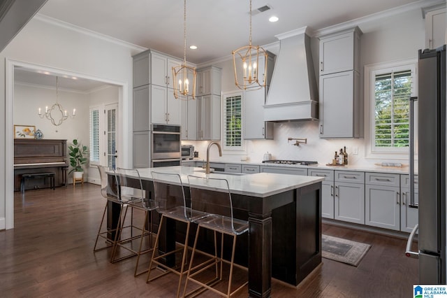 kitchen featuring custom exhaust hood, a center island with sink, sink, dark hardwood / wood-style flooring, and stainless steel appliances