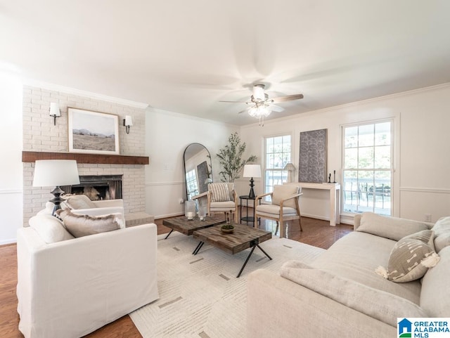 living room with ceiling fan, hardwood / wood-style flooring, a brick fireplace, and crown molding