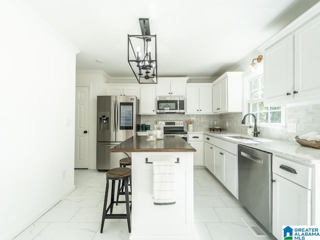 kitchen featuring white cabinetry, appliances with stainless steel finishes, a kitchen island, and sink