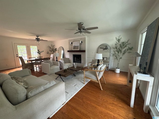 living room with ceiling fan, hardwood / wood-style flooring, a fireplace, and crown molding