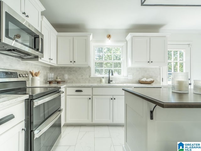 kitchen with stainless steel appliances, white cabinets, tasteful backsplash, and sink