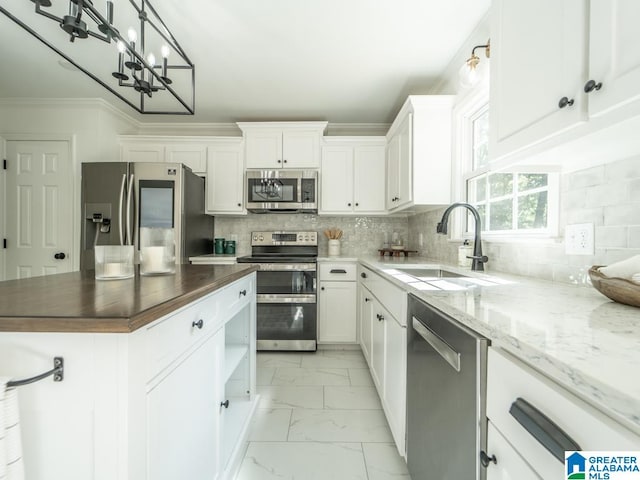 kitchen featuring wood counters, tasteful backsplash, sink, white cabinetry, and stainless steel appliances