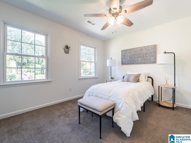 bedroom with ceiling fan, dark carpet, and multiple windows