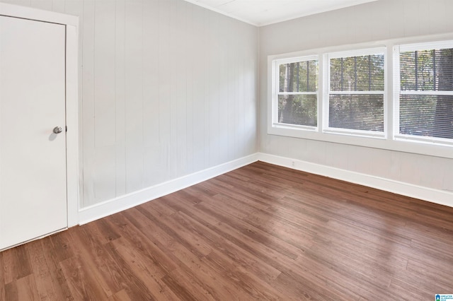 unfurnished room with wooden walls and wood-type flooring