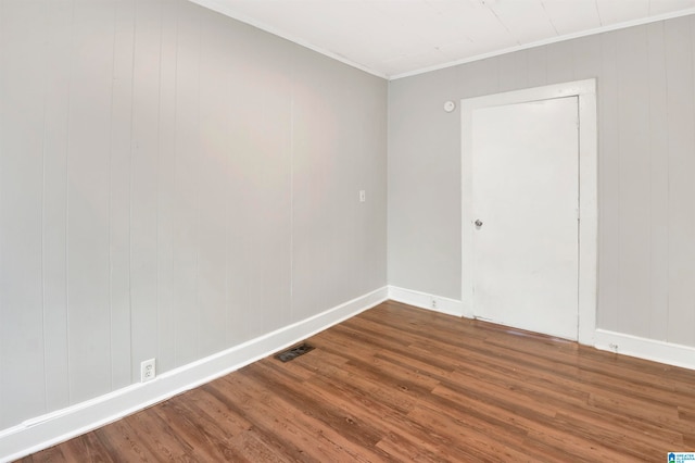 spare room featuring crown molding, hardwood / wood-style flooring, and wooden walls