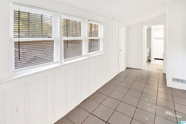 corridor featuring lofted ceiling and light tile patterned flooring