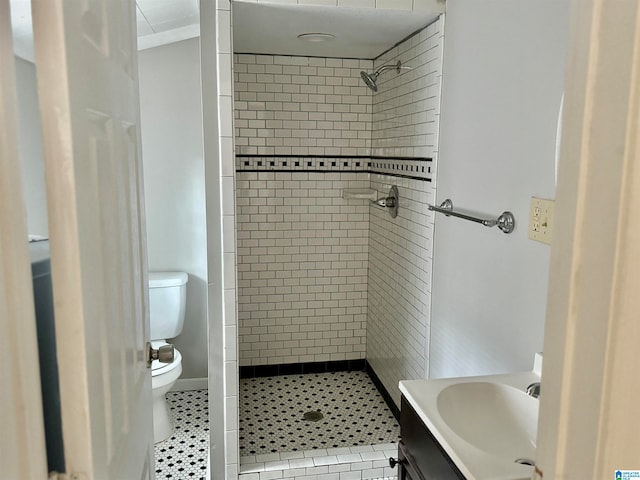 bathroom with vanity, toilet, a tile shower, and tile patterned flooring