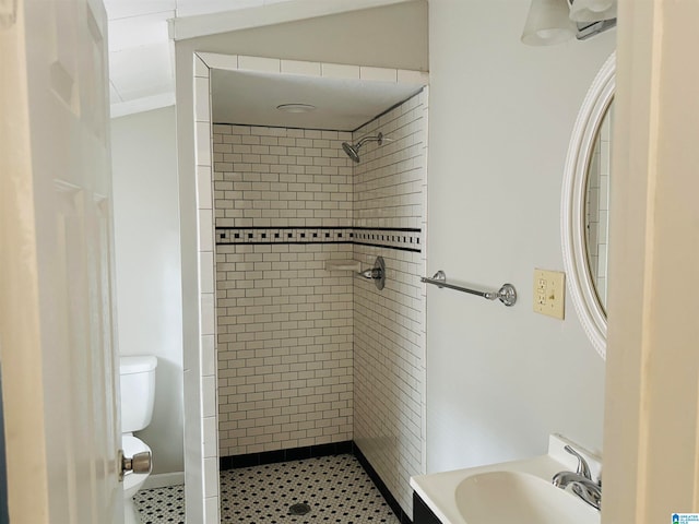 bathroom featuring tiled shower, sink, and toilet