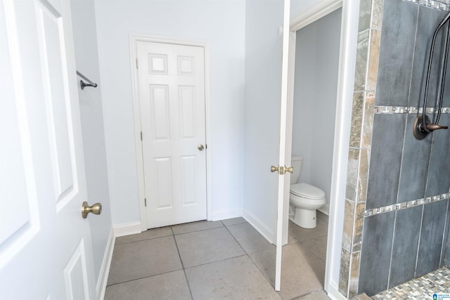 bathroom featuring tile patterned flooring, toilet, and a shower