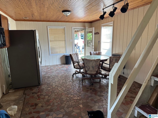 dining space featuring wooden ceiling and wooden walls